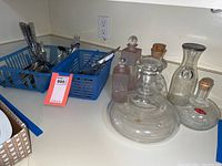 Wide view showing two blue baskets containing flatware and six glass decanters arranged on a countertop