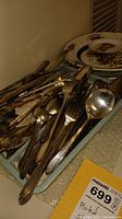 Tray of assorted plated silverware including forks, knives, spoons with decorative handles and some tarnish.