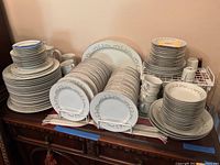 Photo capturing the full set arranged on table with stacks of dinner plates, salad plates, bowls, cups, and saucers.