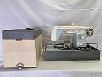 Vintage Arrow sewing machine in blue and white with black base, accompanied by a beige carrying case with blue top.