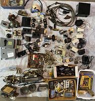 Overview photo showing many vintage electrical components, vacuum tubes, transformers, connectors, switches, and meters.