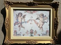 Full view of cherubs wall print inside an ornate golden decorative frame.