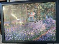 Full shot of framed print showing Monet garden artwork with purple flowers, greenery, and house in background with text Musee d'Orsay Paris and Claude Monet 1840-1926.