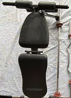 Full view of the Competitor weight lifting chair padded with black cushions and silver frame on a tarp background