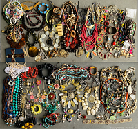 Wide view of assorted costume jewelry showing a large variety of necklaces, bracelets and brooches in multiple colors and materials.