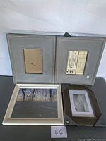Four picture frames arranged with one gray double frame at top and three frames including a large white frame and smaller dark wood frame below.