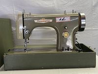 Side view of Kenmore vintage sewing machine showing brand, needle area, knobs and balance wheel