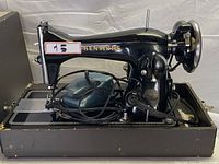 Side view of vintage Kenmore sewing machine with foot pedal and electrical cord resting on base.