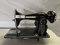 Side view of the vintage black Kenmore sewing machine showing gold trim and adjustment knobs.