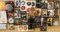 Top-down view of various game DVDs and their cases arranged on the floor. Titles visible include Call of Duty, Battlefield, and miscellaneous game discs.
