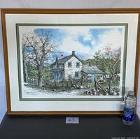 Framed lithograph image showing the full artwork with wooden frame and edges of matting visible, beside a water bottle for scale.