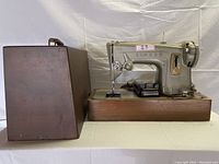 Side view showing the Singer sewing machine with wooden case and foot pedal attached, all placed on a flat surface.
