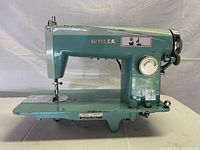 Front and side view of vintage teal White sewing machine showing overall condition, model details and wear.