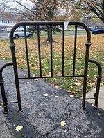 Front view of the metal antique-style headboard showing the rounded top rail and vertical slats.