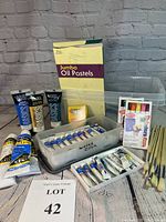 Photo showing full lot with acrylic tubes, brushes, jumbo oil pastels box, Crayola crayons and watercolor tubes arranged together on a tabletop.