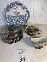 Photo showing four blue and purple plates, matching creamer, covered sugar bowl, and a blue-white lace hanging decoration with a lady figure