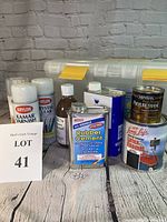 Front view of lot with various varnishes, paints, adhesives and a large plastic tote.