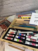Wooden carry box containing 15 tubes of Gouache paints, some pencils, and brushes arranged inside.