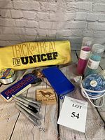 Full lot image showing yellow UNICEF carry bag, US Presidents flashcards, blue pouch, small fan, colored sands, coasters, markers, and fishing line on wood surface