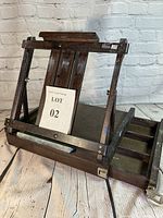 Photo showing front view of dark wooden folding tabletop easel with adjustable supports and canvas holder, with pull-out drawer extended on the side.