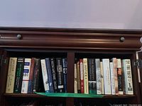 Books arranged on a wooden bookshelf with visible titles relating to historical figures and political themes.