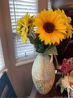 Full view of ceramic vase with faux sunflowers, showing vase's textured patterns and three sunflowers