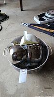 Photo shows a large metal colander containing metal bowls and strainers, and a white ceramic strainer placed inside it.