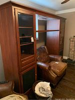 Full view of the tall wooden entertainment cabinet showing left side glass door shelves, central open section, and overall shape.
