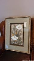 Full view of the framed floral art piece showing frame and tags.