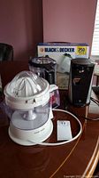 Photo showing Black & Decker CJ630 juicer, electric can opener, KitchenAid food chopper on table with MX350 mixer box in background