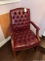 Full view of the wood-framed chair with red tufted leather upholstery on seat and backrest, showing armrests and overall condition.