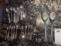 Full laid out image showing teaspoons, forks, and salad servers with intricate floral and twisted pattern handles.