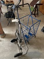 Blue metal trolley and silver metal dolly photographed from an angle, showing handles and wheels.