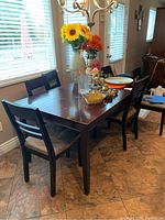 Darker finished wooden rectangular table with six matching wooden chairs around it. Table top visible with some decorative items.