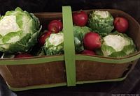 Top view of the basket containing artificial apples and cabbages showing item details and basket construction.