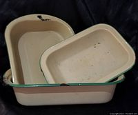 Three beige enamelware pans with green trim, nested, showing overall condition including chips and wear.
