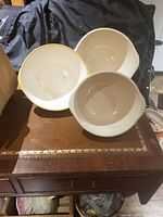 Three ceramic bowls, one white plain, two yellow with embossed pattern, shown from top down and angles.