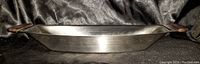 Side view of one stainless steel tray showing metal body with wooden handles at each end.