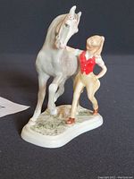 Side angle view of porcelain figurine showing girl in red vest with horse.