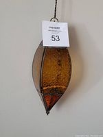 Front view of amber stained glass lantern hanging against wall with auction tag