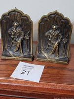 Pair of bronze book ends depicting Charles Dickens seated, showing detailed carvings and inscriptions.