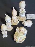 Full set of five Enesco baby porcelain figurines and a piglet on black background.