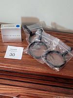 Photo shows three Hasselblad focusing ring handles in plastic bags next to the original silver Hasselblad box.