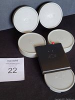 Photo of five gray 70mm lens caps and one metal rear camera body cover.