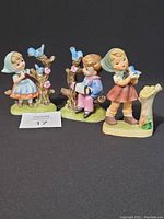 Front view of three porcelain figurines depicting children with blue birds, showing full figures and colors