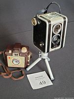 Two vintage Kodak Brownie cameras side by side with a rental lot card, one is on a Mini Sony tripod (not included).