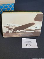 Closed rectangular metal tin with vintage airplane photo on the lid