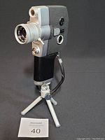 Photo showing the camera on tripod from right side with manual zoom visible, Fujica brand on lens barrel.