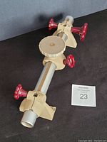 Side angle view of Linhof Kardan tubular monorail showing red adjustment knobs, beige support clamps, and round mounting plate.