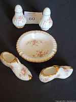 Salt and pepper shakers, ashtray, and two decorative shoe figurines shown from front angle on black background.